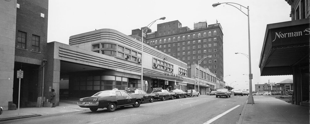 Taxis lined up at the curb outside the streamlined Union Bus Station, with a tall hotel behind.